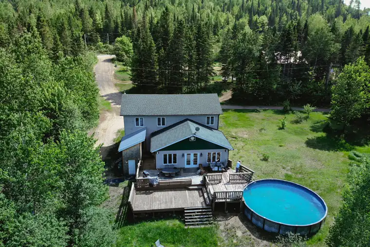 Vue aérienne d'une maison avec piscine entourée de forêt