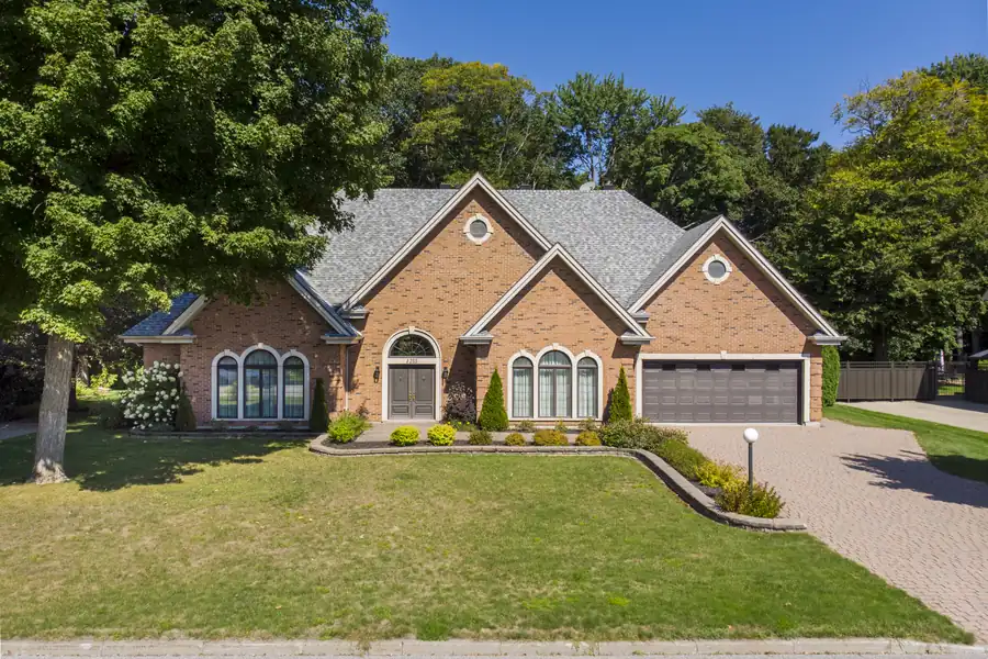 Façade de maison en brique avec garage double et aménagement paysager