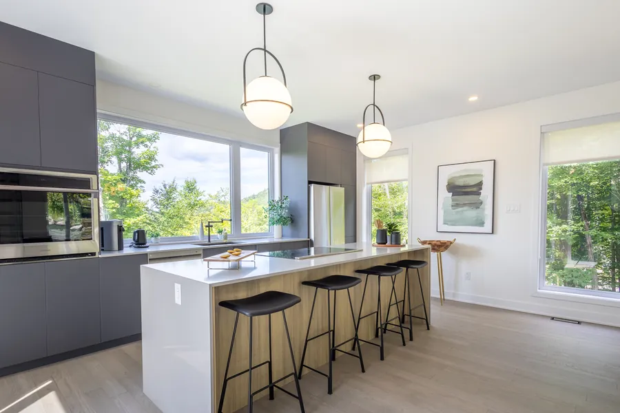 Cuisine moderne avec îlot de quartz, tabourets et armoires foncées