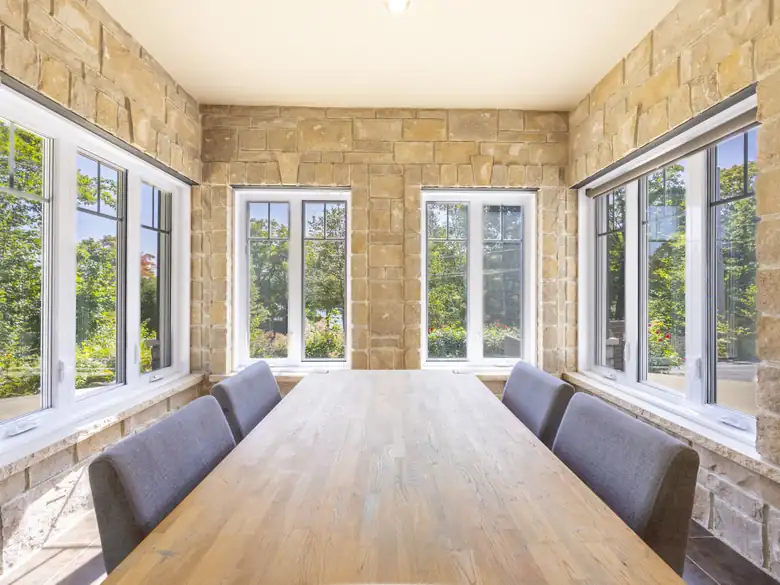 Salle à manger avec mur de pierre et fenêtres pleine hauteur